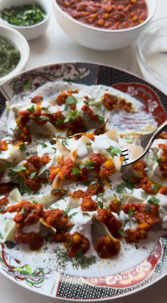 a plate full of Mantu with a sauce being poured over it